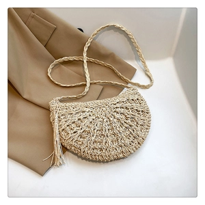 Detail of hand-woven beige straw saddle bag with tassels and braided shoulder strap