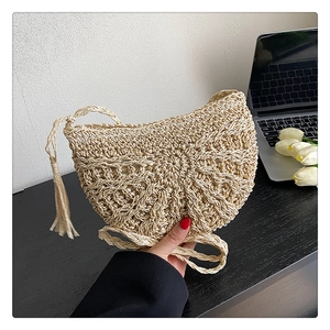 Detail of hand-woven straw shoulder bag with long tassels and intricate crescent patterns