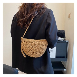 Detailed back view of a brown woven straw crescent bag styled on a black blazer