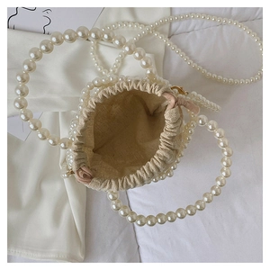 Top view of a beaded mini bucket bag featuring large white pearls and a pink drawstring liner