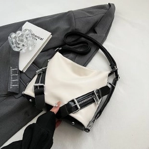 Modern black and white contrast leather handbag with silver buckles on a formal suit background