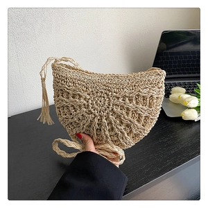 Handmade beige straw half-moon shoulder bag with hollow knit patterns and tassels