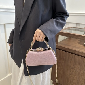 Detail of pink glitter clutch with pearl handle, golden chain and crown-shaped clasp