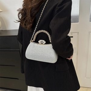 Macro view of sparkly silver clutch featuring a golden chain and crown crystal buckle