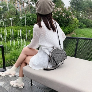 Outdoor lifestyle shot of a black rhinestone crossbody bag with metal chain strap