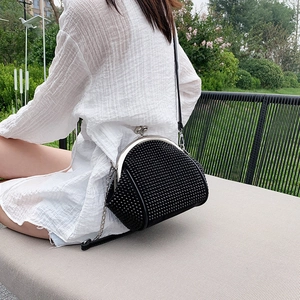 Detail of black crossbody bag with silver metal kiss lock and studded matte texture