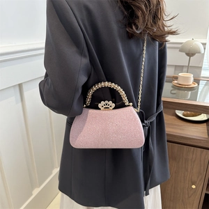 Pale pink glitter clutch with rhinestone handle and crown clasp worn with chain strap