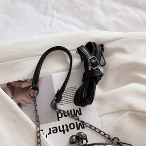 Detail of black PU leather strap, metallic chain, and spherical clasp for crossbody bag