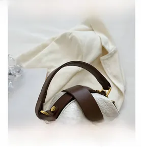 Detail of contrast-color shell bag featuring animal pattern leather and gold hardware
