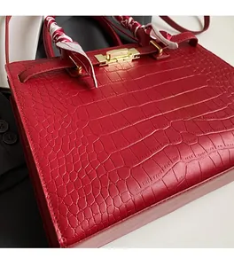 Close-up of dark red crocodile embossed handbag with printed silk scarf on handle