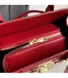 Detail of red crocodile texture handbag featuring a smooth golden metal zipper closure