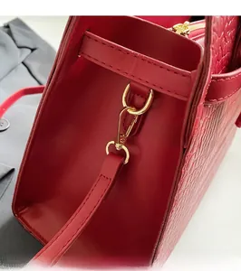 Close-up of red leather handbag with crocodile pattern texture and golden metal hardware