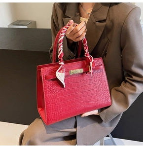 Detail of red crocodile texture tote with silk scarf handle and gold metal twist lock