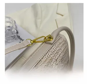 Close-up of premium gold hardware hook on cream woven shoulder bag with leather trim