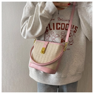 Close-up of pink and beige woven straw bucket bag with gold lock and leather details