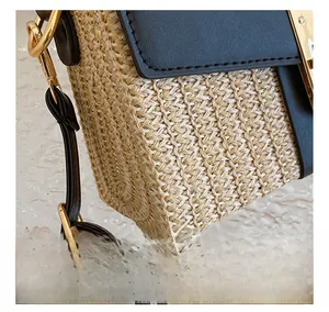 Detail showing the straw woven texture and premium black leather stitching on the bag
