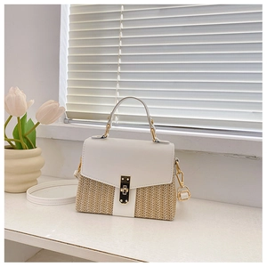 Close-up of woven straw and white leather bag with gold metal clasp on a windowsill