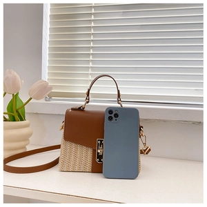 Close-up of woven straw and brown leather mini bag with gold metal twist lock