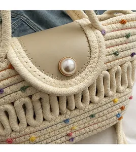 Détail du sac tressé avec pompons colorés, rabat en cuir et boucle en perle élégante