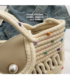 Détail d'un sac tressé avec des pompons colorés et une boucle en grosse perle