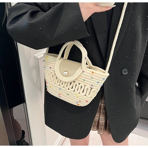 Gros plan d'un sac bandoulière tissé avec pois colorés et bouton perle sur blazer