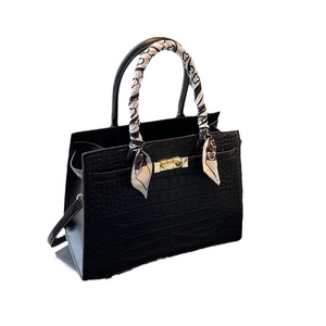 Elegant black crocodile pattern handbag with gold clasp and decorative silk scarf