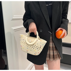 Détail d'un sac en paille tressée beige avec des pois colorés et un fermoir grosse perle