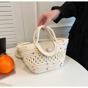 Détail du sac tressé avec pompons colorés et fermoir à perle élégant de style bohème