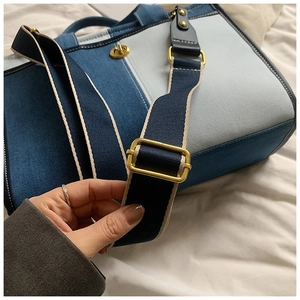 Détail du cabas en denim bicolore avec fermoir rotatif doré et bandoulière réglable