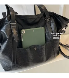 Gros plan de la poche arrière du cabas en cuir noir contenant une tablette verte
