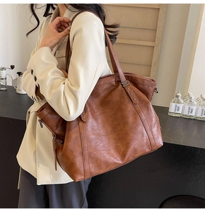 Détail du sac cabas en cuir marron avec rivets en étoile et texture vintage sur la bandoulière