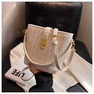 Minimalist woven straw bucket bag with white leather trim and gold hardware crossbody