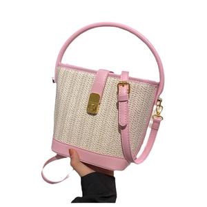 Women's woven straw bucket bag with pink leather trim and adjustable crossbody strap