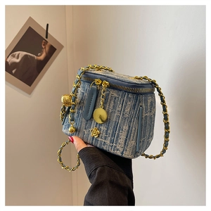 Macro detail of denim texture on mini crossbody bag with gold chain and flower charm