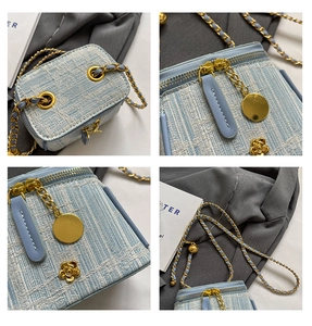 Detail of light blue tweed mini box bag featuring gold chain strap and floral hardware