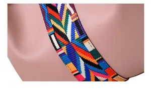 Gros plan d'une bandoulière tissée colorée sur un sac en cuir à texture grainée