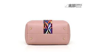 Détail du dessous d'un sac en cuir rose poudré avec rivets dorés et sangle tissée