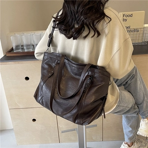 Grand sac cabas marron foncé avec clous en étoile et bandoulière porté par mannequin