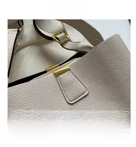 Detailed macro view of off-white lychee leather texture and shiny gold metal buckle