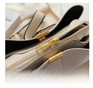 Detailed close-up of smooth gold zipper and pebble leather texture on chic handbag