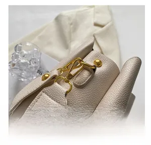 Close-up of cream lychee leather handbag with premium gold hardware and shoulder strap