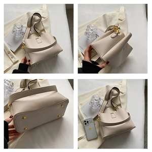 Detail of beige lychee grain leather bag showing metal base studs and adjustable strap