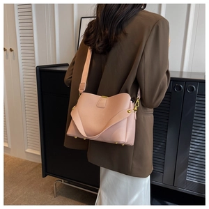 Detail of light pink lychee pattern crossbody bag with golden hardware and wide strap