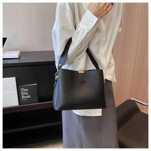 Close-up of black lychee grain leather bucket bag with wide strap and gold hardware