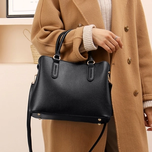 Close-up of black lychee grain tote bag with gold protective studs and fine stitching