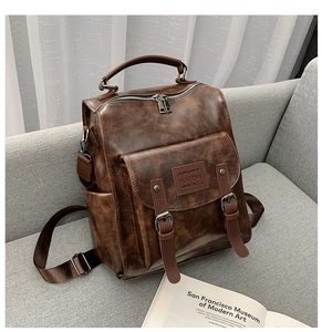 Detail view of vintage brown leather texture and metal buckle on large backpack