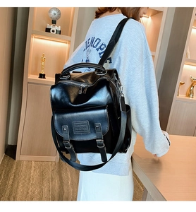 Detail of black versatile backpack showing premium synthetic leather texture and buckles