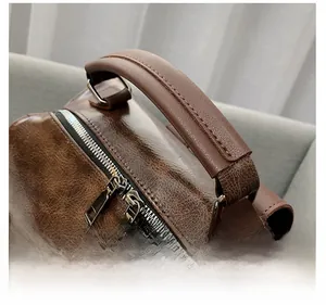 Close-up of brown leather backpack handle and silver metal zippers with fine stitching