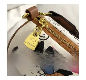 Détail du zip en métal doré et du logo sur le sac cylindre avec graffiti