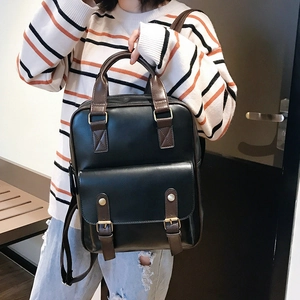 Detailed close-up of retro black and brown leather backpack with brass metal buckles